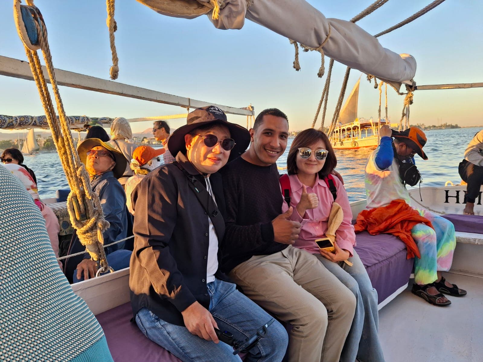 Guests sitting with their Egyptian guide on a felucca as the sun sets over Luxor